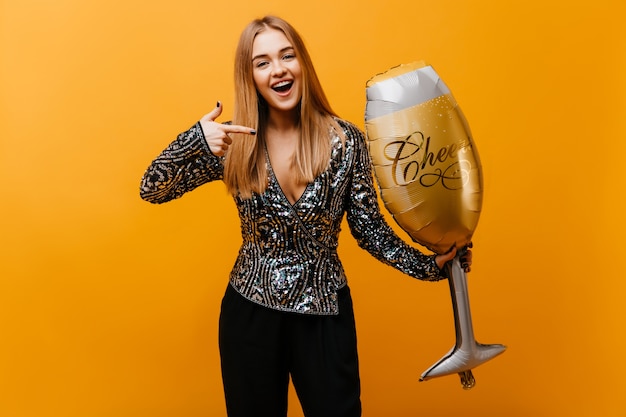 Femme glamour de bonne humeur exprimant des émotions positives après la fête. Superbe femme aveugle tenant un verre à vin orange.