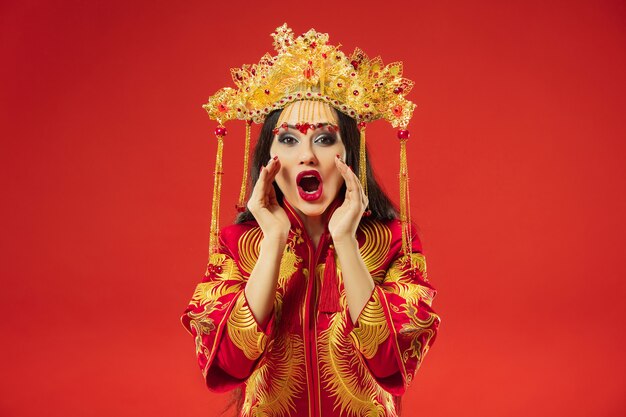 Femme gracieuse traditionnelle chinoise au studio sur mur rouge