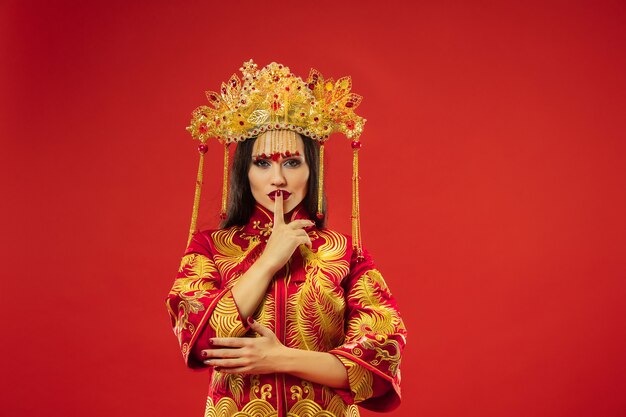 Femme gracieuse traditionnelle chinoise au studio sur mur rouge