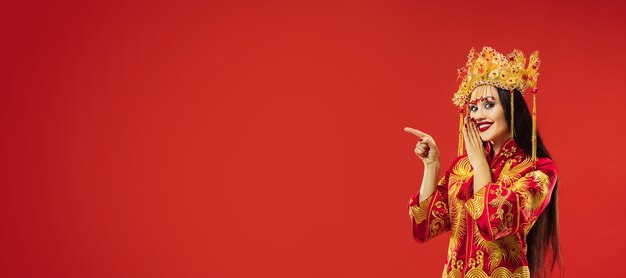 Femme gracieuse traditionnelle chinoise au studio sur mur rouge