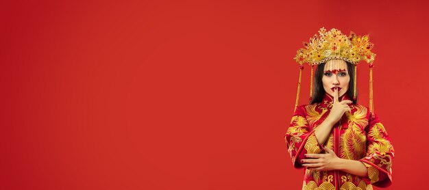 Femme gracieuse traditionnelle chinoise au studio sur rouge.