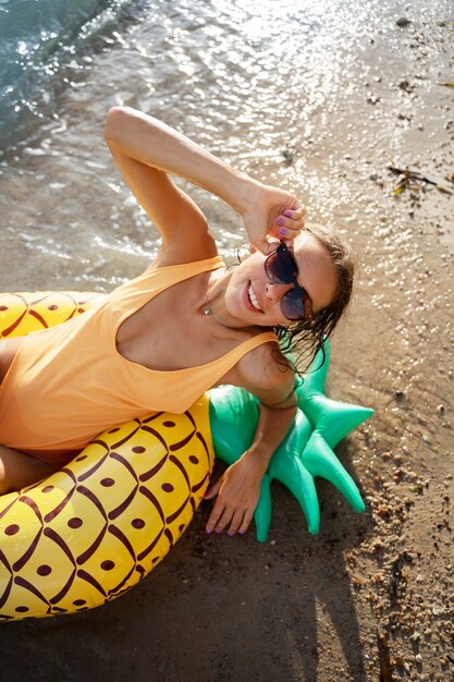 Femme grand angle allongée sur un flotteur d'ananas