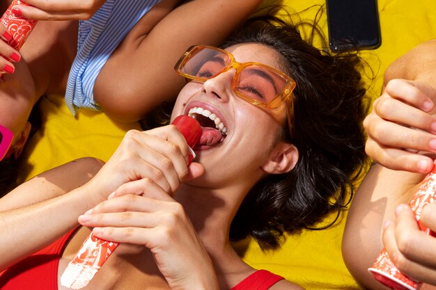 Femme grand angle mangeant des glaces sur la plage