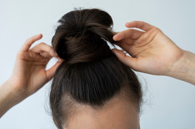 Femme grand angle organisant un chignon désordonné