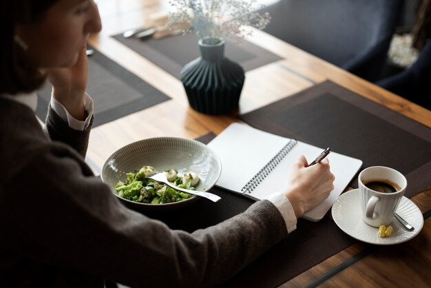 Femme grand angle prenant des notes sur un cahier