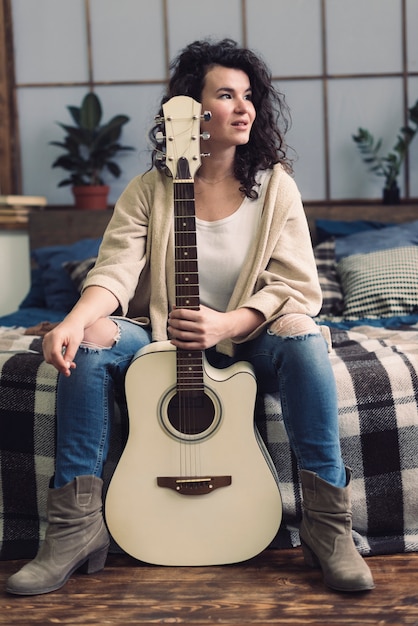 Photo gratuite femme avec une guitare sur le lit