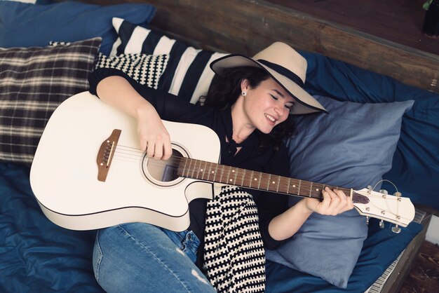 Femme avec une guitare sur le lit