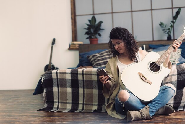 Femme avec guitare et téléphone portable