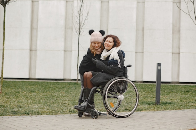 Femme handicapée en fauteuil roulant avec sa fille. Famille marchant dehors au parc.