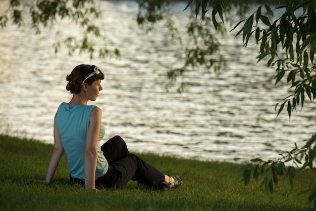 Femme sur l&#39;herbe à côté d&#39;un lac