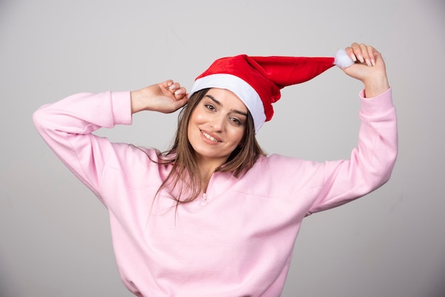 Une femme heureuse au chapeau rouge du père Noël posant.