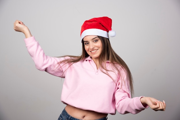 Une femme heureuse au chapeau rouge du père Noël posant.