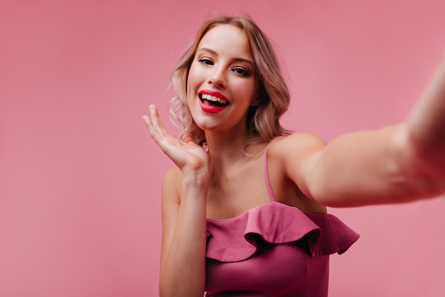 Femme Heureuse Aux Cheveux Blonds S'amusant En Studio Et En Prenant Une Photo D'elle-même