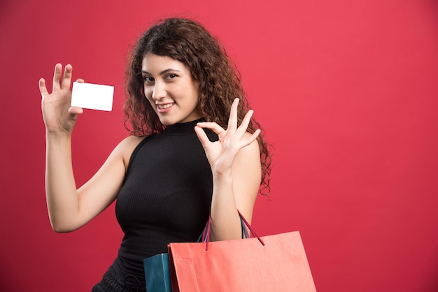 Photo gratuite femme heureuse avec beaucoup de sacs et carte bancaire sur rouge