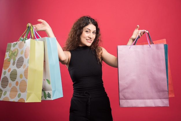 Femme heureuse avec beaucoup de sacs sur fond rouge