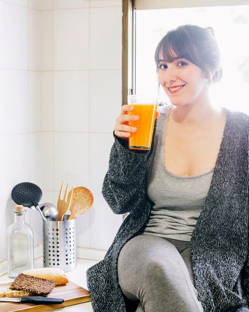 Femme heureuse, boire du jus dans la cuisine