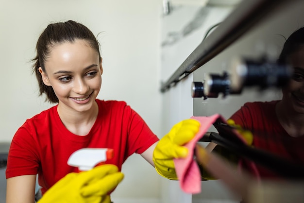 femme heureuse avec une bouteille de nettoyant en spray nettoyant four à la cuisine à domicile