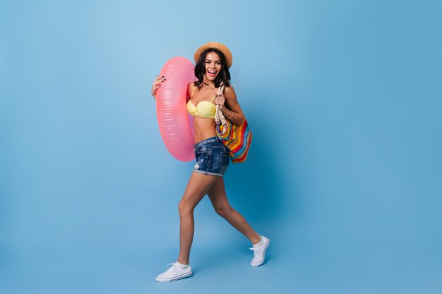 Femme heureuse avec cercle de natation dansant sur fond bleu