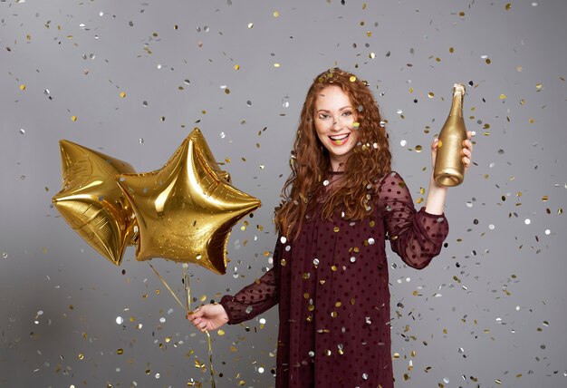 Femme heureuse avec champagne et ballons en forme d'étoile