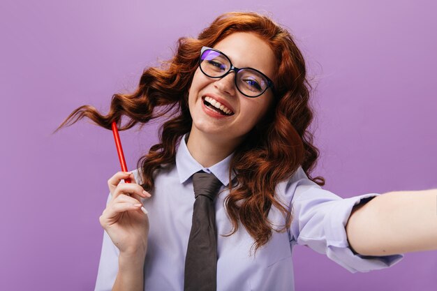 Femme heureuse en chemise et lunettes riant sur le mur violet