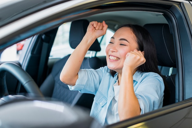 Une femme heureuse dans un concessionnaire de voitures