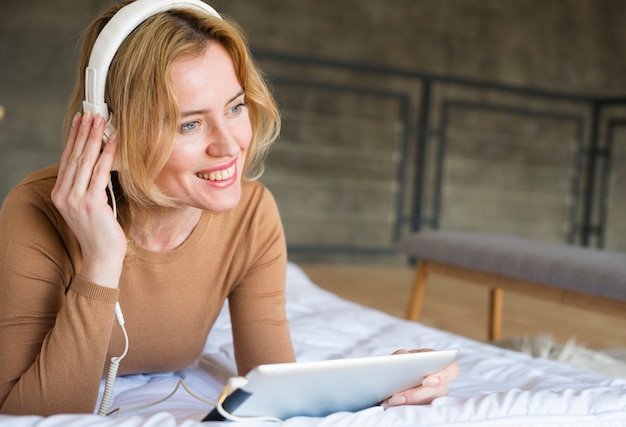 Photo gratuite femme heureuse dans les écouteurs, écouter de la musique sur le lit