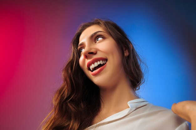 La femme heureuse debout et souriant contre coloré.