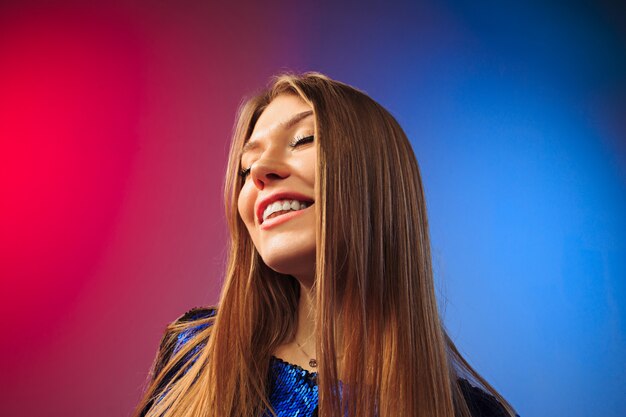 La femme heureuse debout et souriant contre un mur de couleur