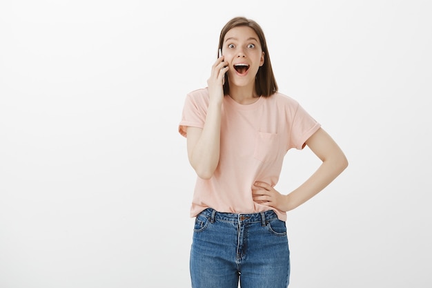 Femme heureuse excitée, parler au téléphone mobile et entendre de bonnes nouvelles