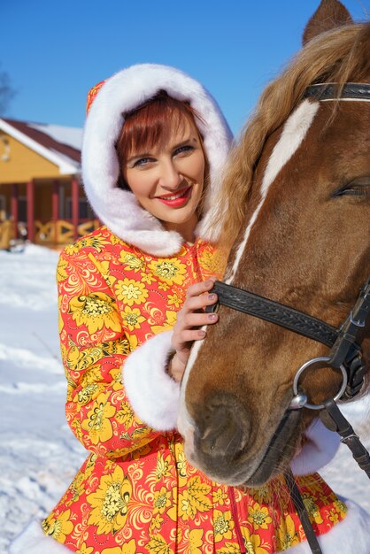 Femme heureuse en hiver avec un cheval dans la rue