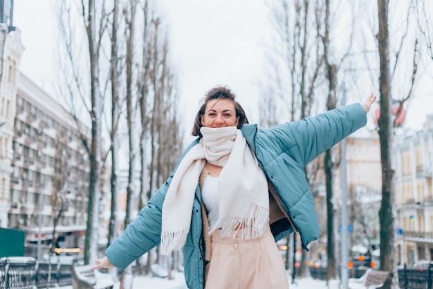 Femme heureuse en hiver sur la ruelle de la ville enneigée