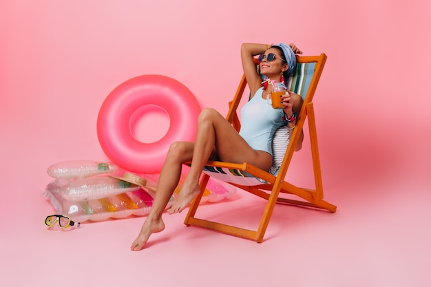 Photo gratuite femme heureuse en maillot de bain allongé dans une chaise longue