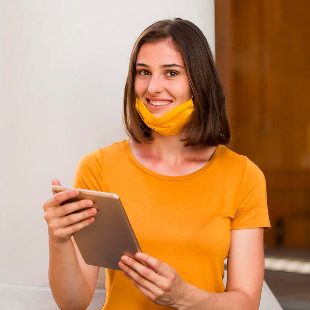 Femme heureuse avec masque médical jaune