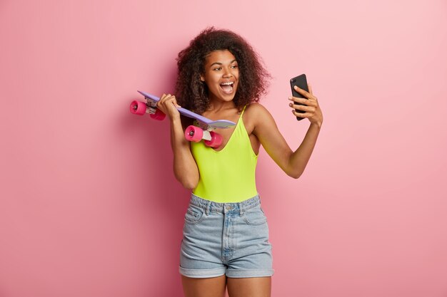 Femme heureuse millénaire à la mode tient la planche à roulettes