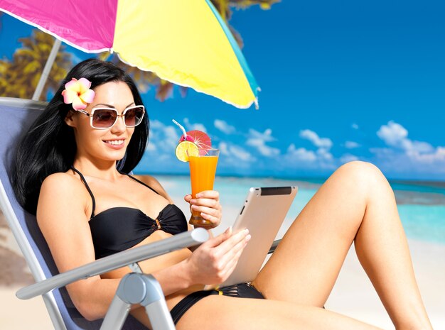 Femme heureuse sur la plage avec ipad.