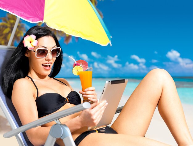 Femme heureuse sur la plage avec ipad.