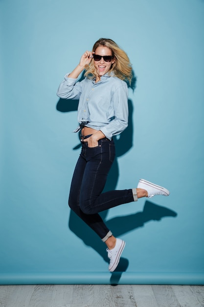 Femme heureuse pleine longueur en chemise et lunettes de soleil