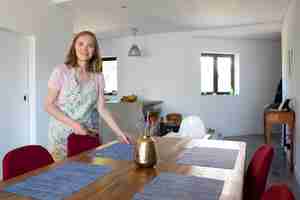 Photo gratuite femme heureuse portant un tablier, servant une table à manger pour un dîner en famille à la maison. manger à la maison ou au concept de femme au foyer