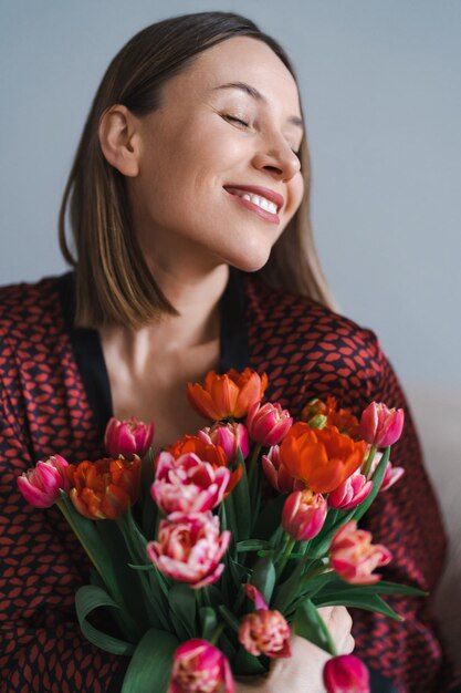 Femme heureuse profitez d'un bouquet de tulipes Femme au foyer bénéficiant d'un bouquet de fleurs et de l'intérieur de la cuisine