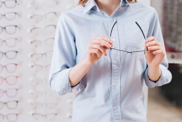 Femme heureuse à la recherche de nouvelles lunettes chez l&#39;optométriste