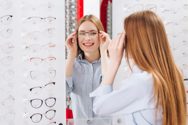 Femme heureuse à la recherche de nouvelles lunettes chez l&#39;optométriste