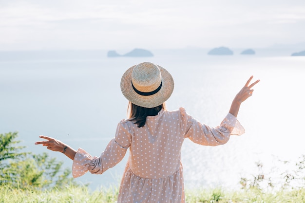 Femme heureuse en robe mignonne d'été et chapeau de paille en vacances avec vue exotique tropicale