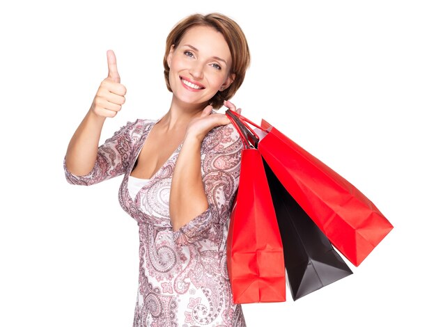 Femme heureuse avec des sacs à provisions après le shopping montrant le geste des pouces vers le haut