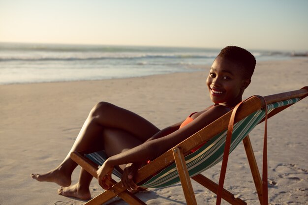 Femme heureuse se détendre sur une chaise de plage sur la plage