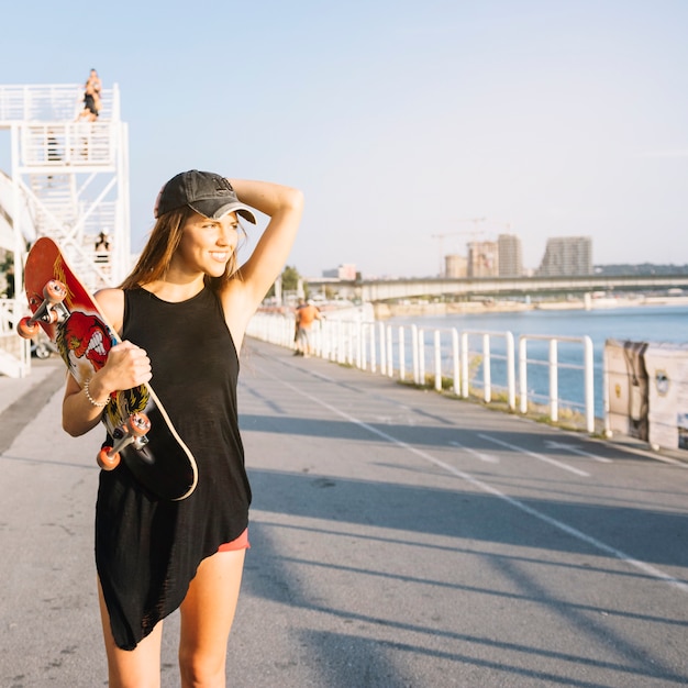 Femme heureuse avec skateboard marche dans la rue