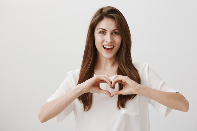 Femme heureuse souriante montrant le geste du coeur