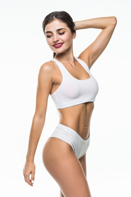 Femme heureuse en sous-vêtements blancs fit isolé sur mur blanc