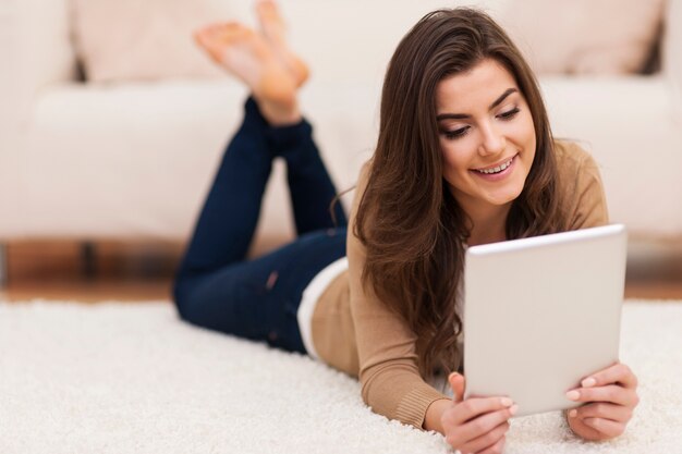 Femme heureuse sur tapis à l'aide de tablette numérique