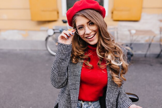 Femme heureuse en tenue décontractée à la mode à la recherche d'appareil photo avec un sourire heureux