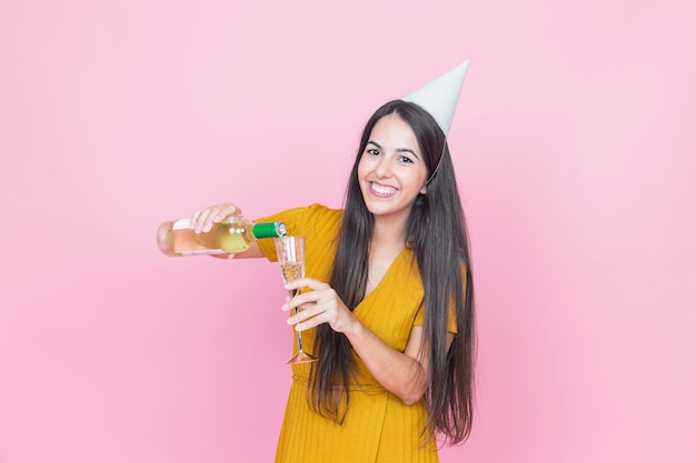 Femme heureuse, verser la boisson dans le verre sur fond rose